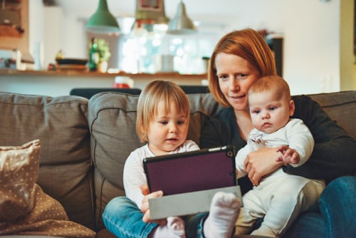 Symbolbild: Mutter mit zwei kleinen Kindern auf einem Sofa