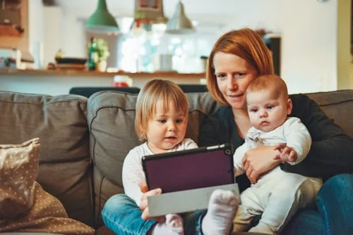 Symbolbild: Mutter mit zwei kleinen Kindern auf einem Sofa